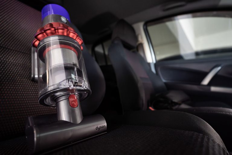 A Dyson cordless vacuum used in cleaning the car chairs