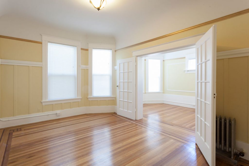 A gorgeous empty living room with wooden flooring, tan painted walls and white wooden painted door