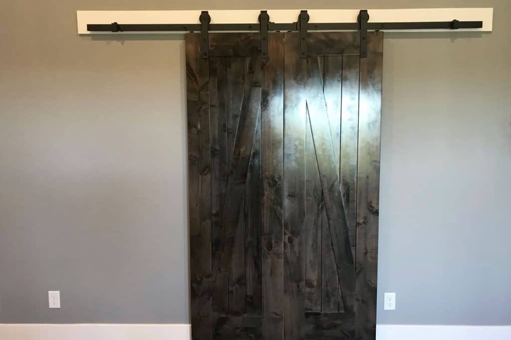 A dark hardwood barn door with a black color sliding mechanism