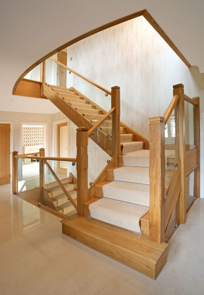 A modern oak and glass staircase in the marble floored entrance hall of an expensive new home