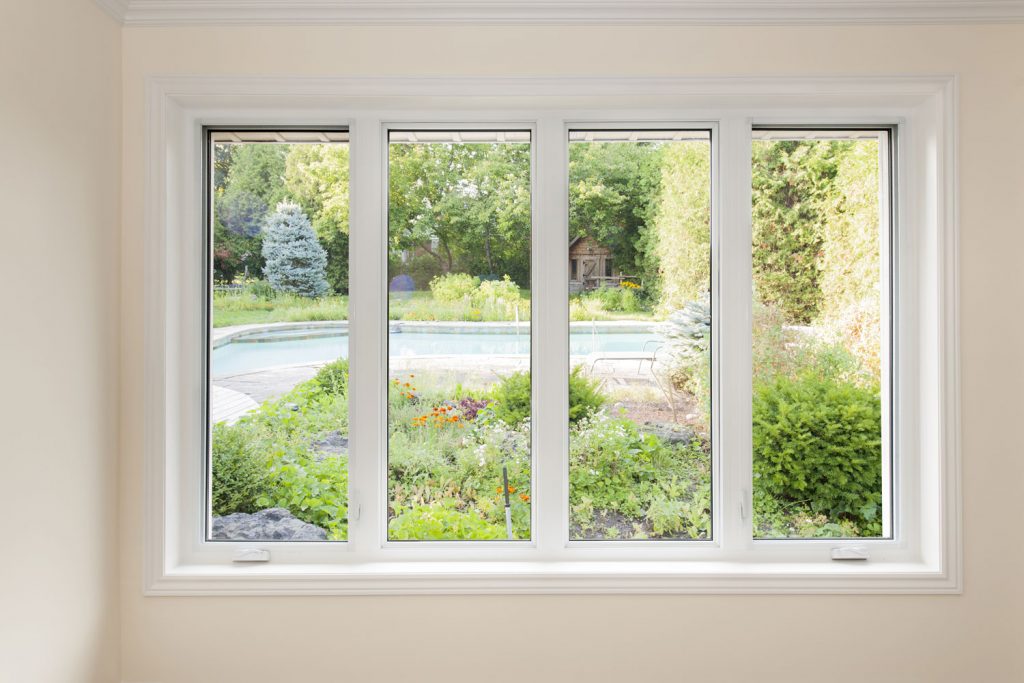 A panoramic white framed window with a view of the garden and pool