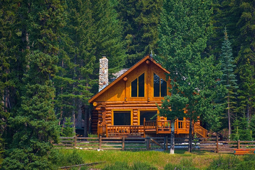 A two story log cabin house in the middle of the forest