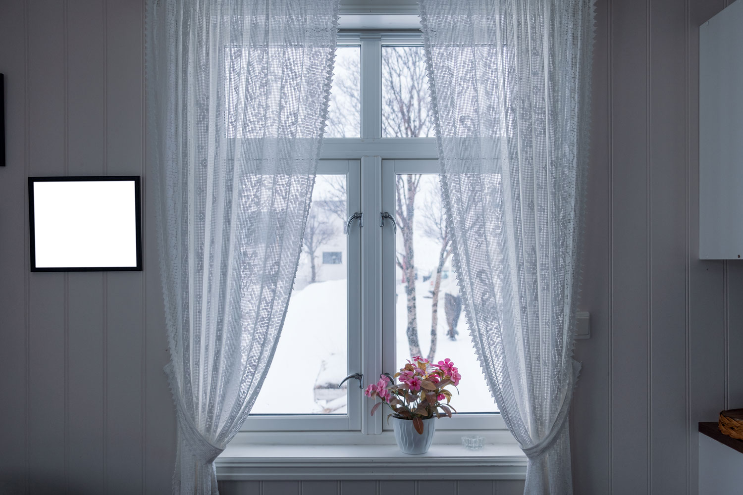 A white framed casement window with white curtains decorated with flowers, Do Casement Windows Open In Or Out? [And How Far Do They Open?]