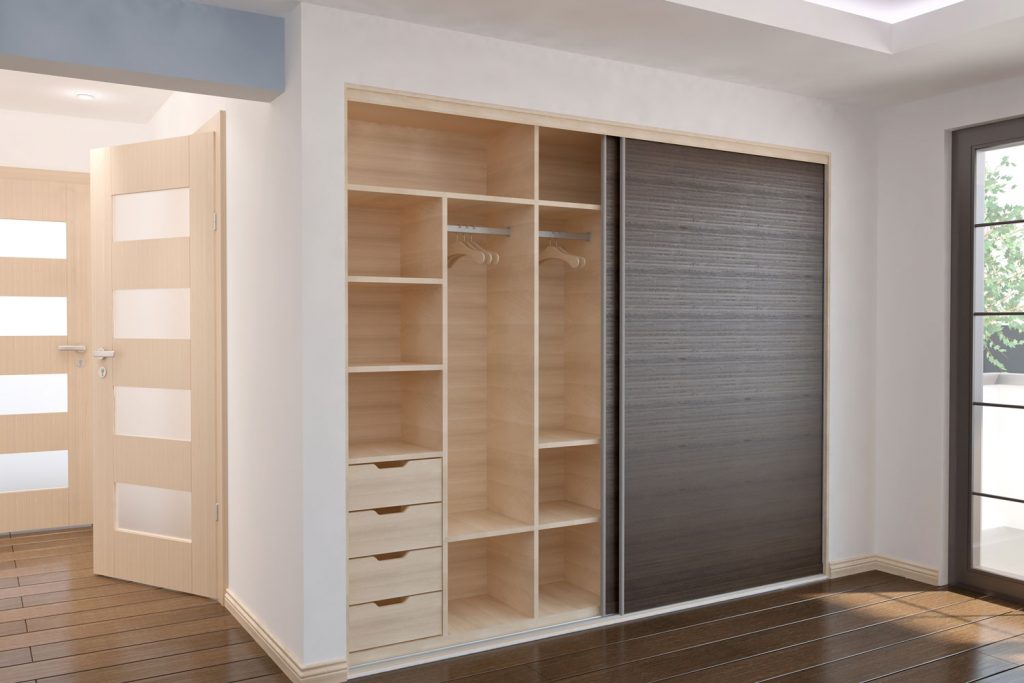 An empty walk in closet with a wooden laminated sliding door