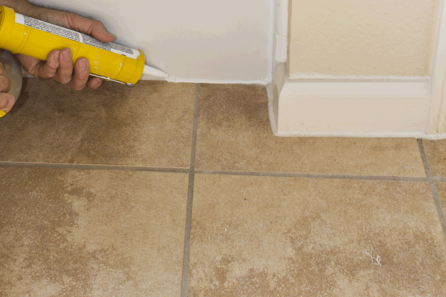 Contractor sealing shower pan to keep water from seeping through the ceramic tile and rotting the floor, How Much Gap Between Shower Pan And Tile? [And How To Fill It In]