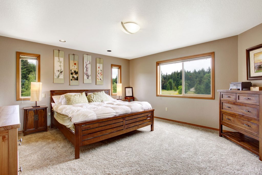 Cozy bathroom interior with double wooden bed and beige carpet floor