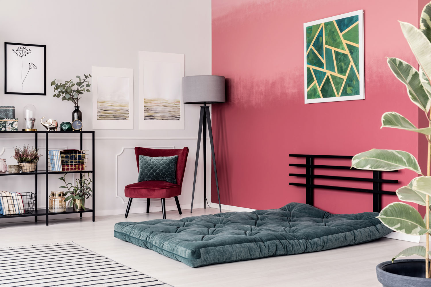 Emerald green futon with pink pillows on the floor against red, ombre wall in elegant living room interior with gray lamp and velvet chair, 11 Great Colors That Go Well With Burgundy