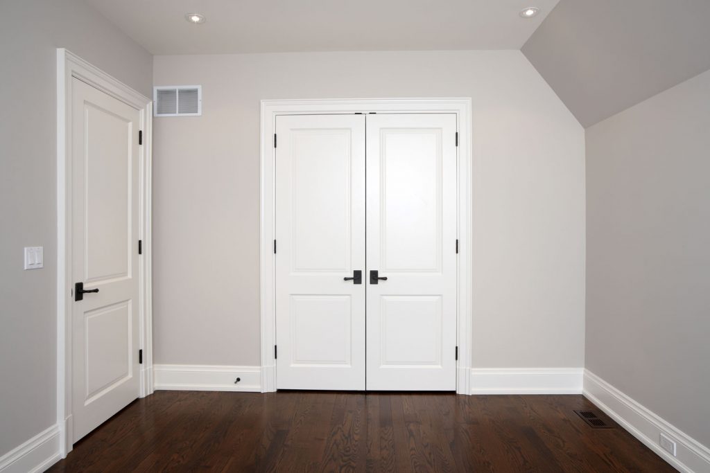 Empty room with gray walls, hardwood flooring and white painted closet door