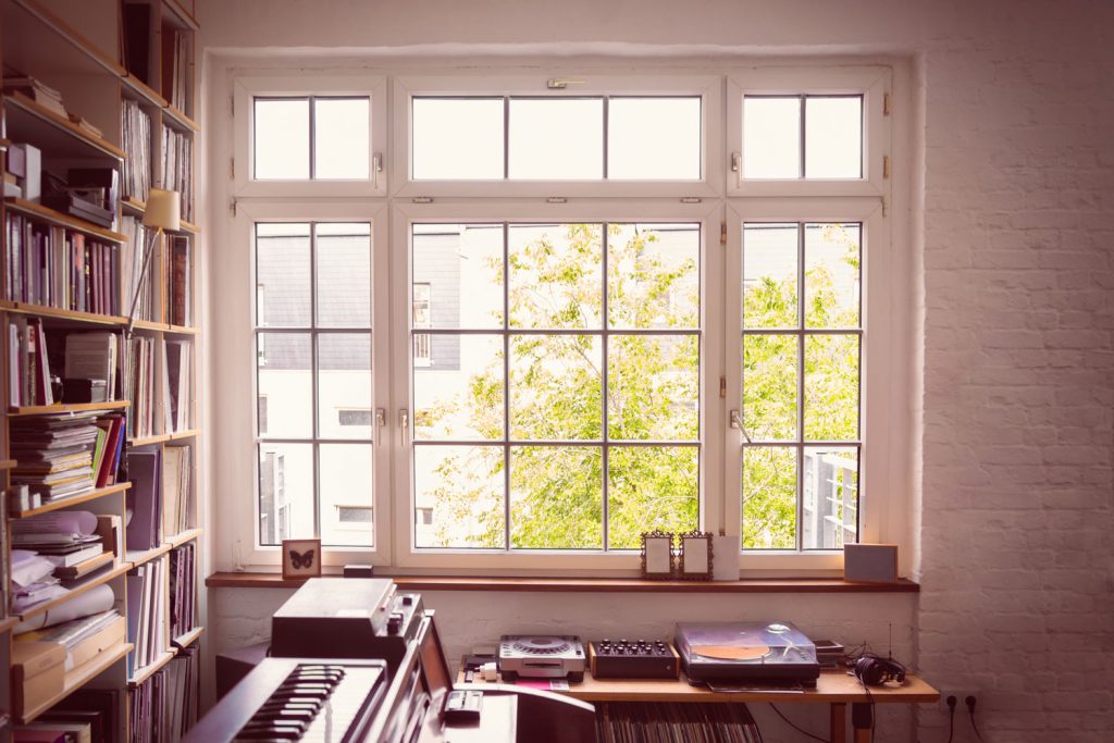Large multi-panel casement window illuminating a lived-in music room.