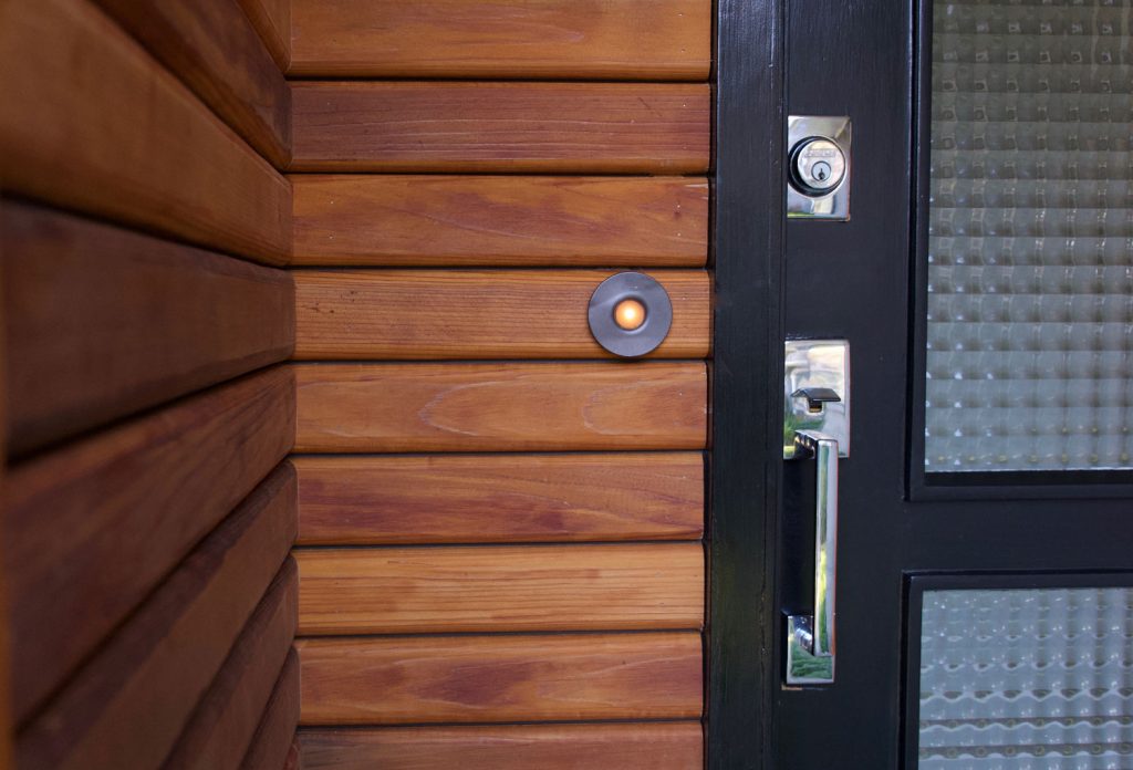 Mid-century modern black door with chrome handles and horizontal, cedar siding at a home's entry