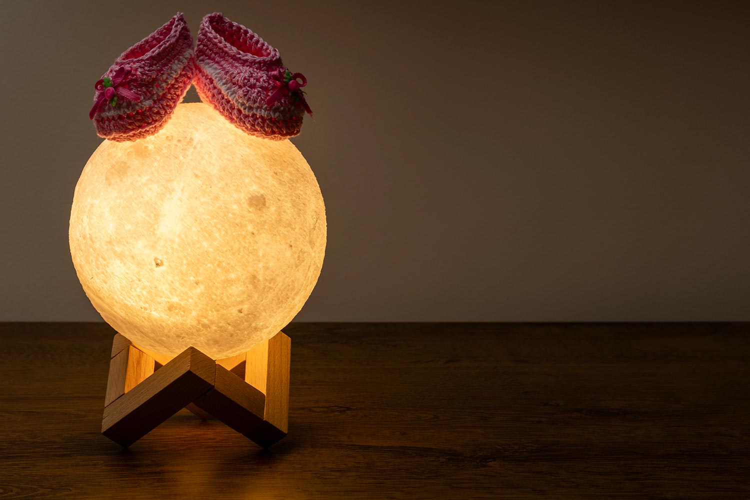Moon lamp and baby slipper on wooden table