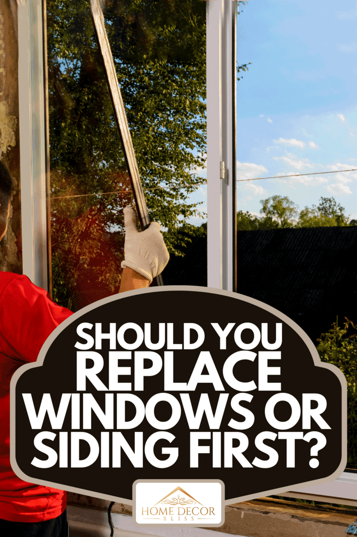 A worker inserts glass into the window frame, Should You Replace Windows Or Siding First?