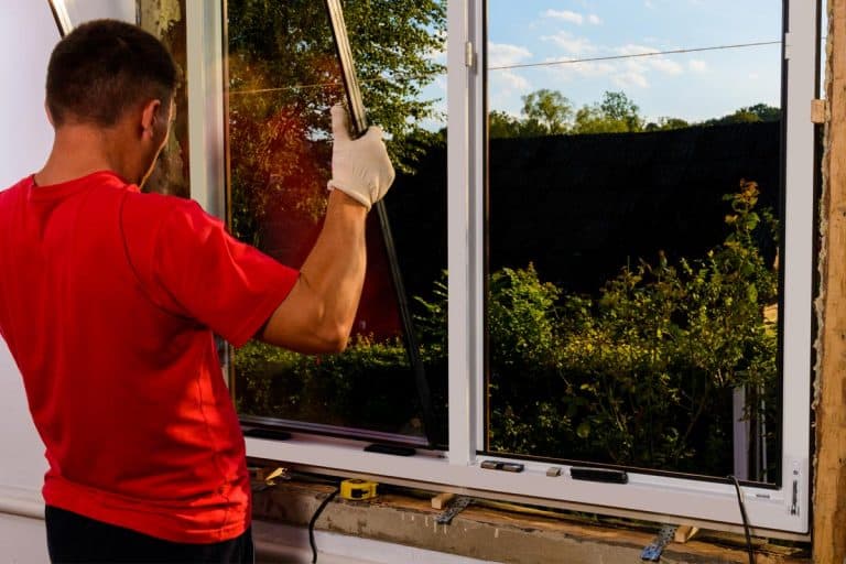 The worker inserts glass into the window frame, Should You Replace Windows Or Siding First?
