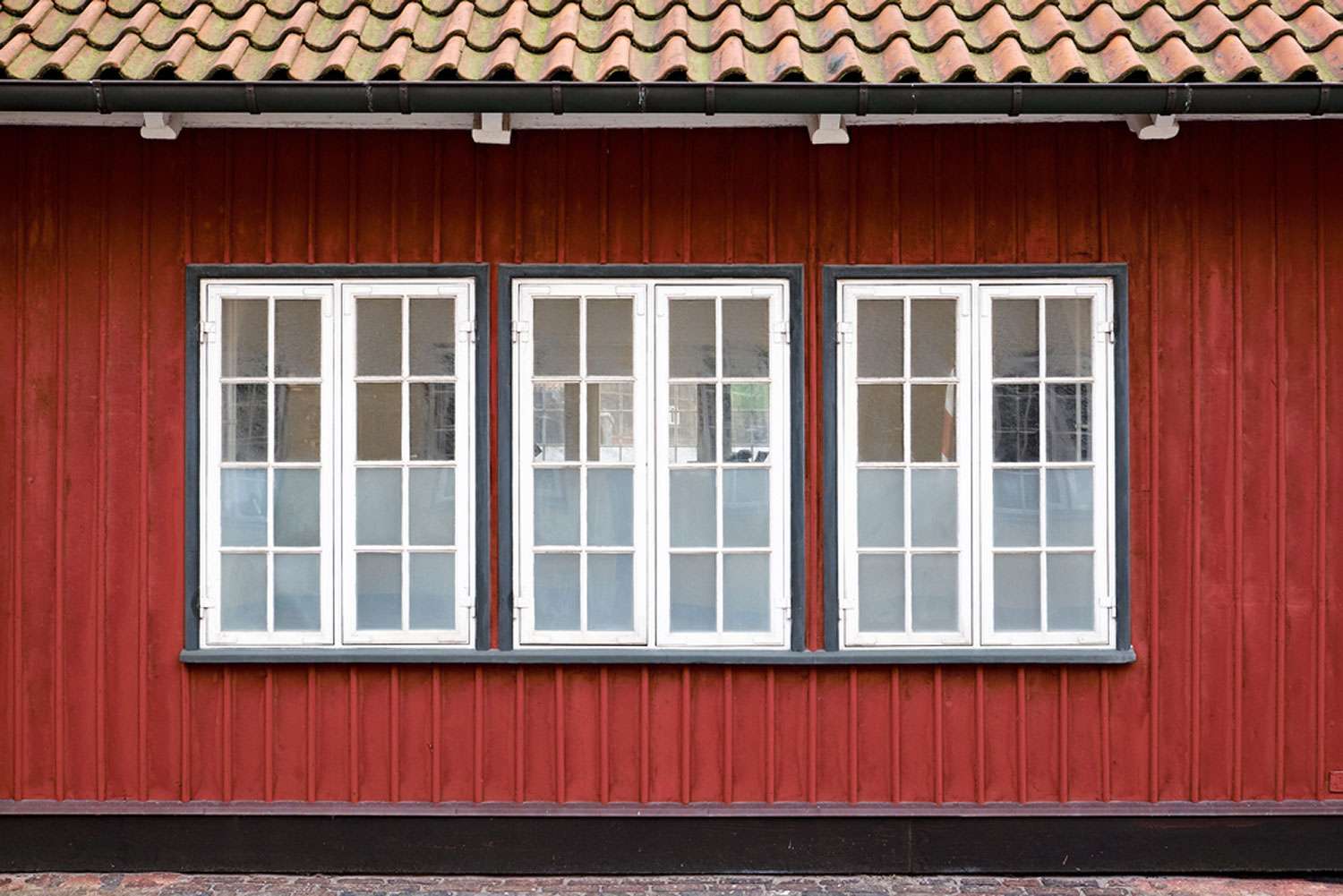 Three white painted casement windows with partly frosted glazing, in a red painted wood plank facade, How Big Can A Casement Window Be?