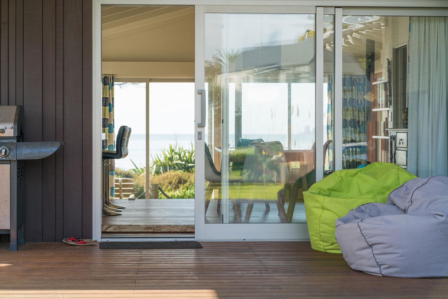 White aluminum sliding door photographed from the patio with a gorgeous overlooking view of the living room and sea