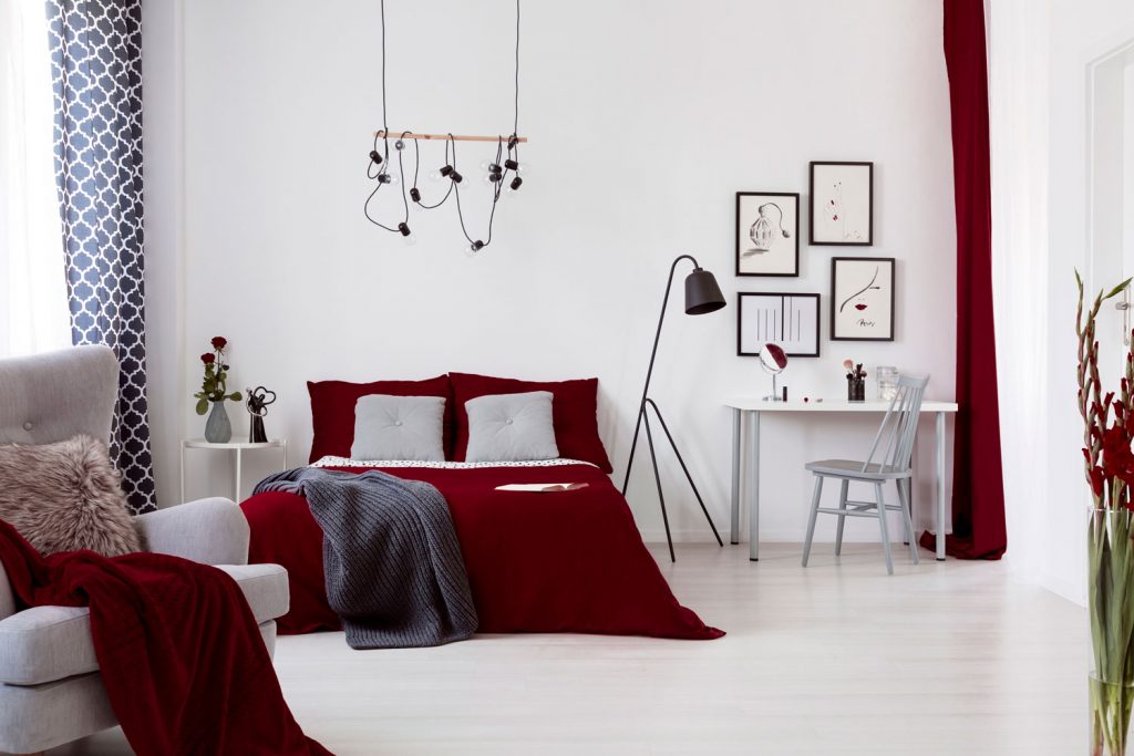 White and burgundy contemporary bedroom interior with a bed dressed in cotton linen and pillows