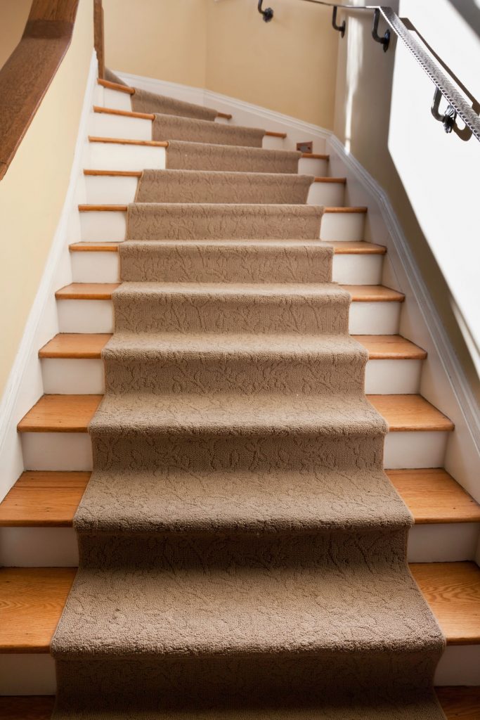 hardwood stairs that disappear at the top around a curve with an iron railing