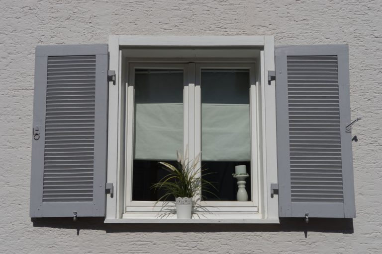 old white double casement window with grey shutters in a plastered and white painted wall, Do Casement Windows Have Weep Holes?