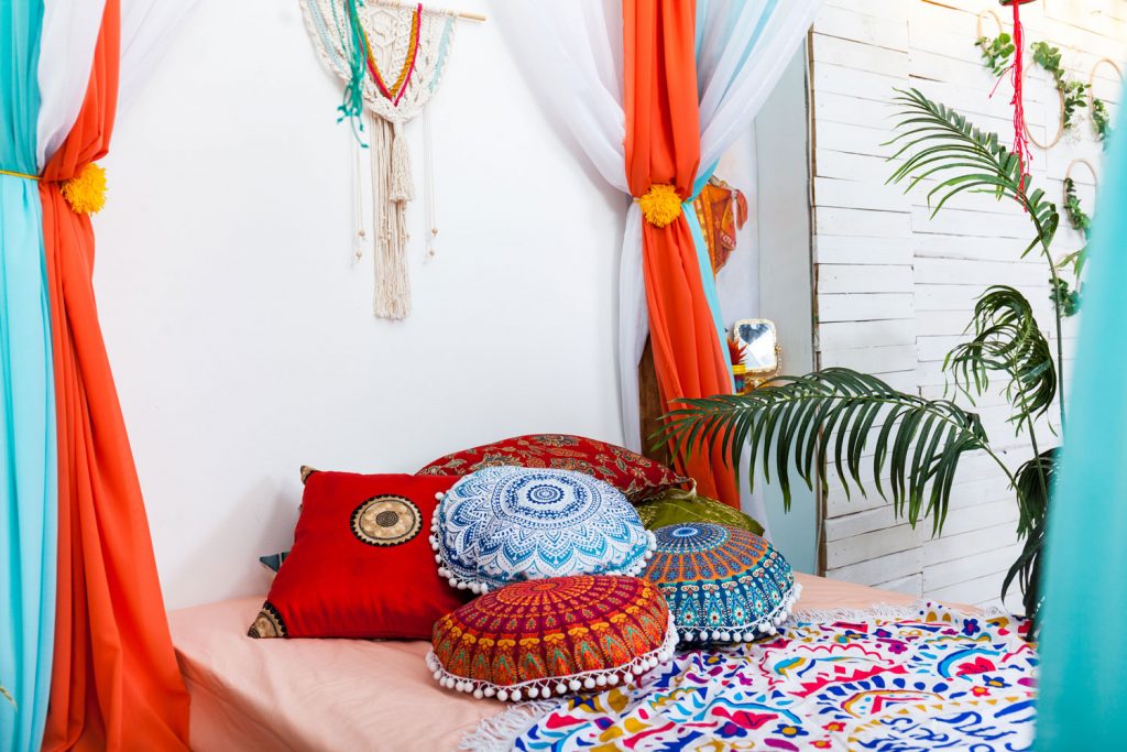 A bedroom in Marrakech with bright colored pillows and gorgeous curtain along with home plants