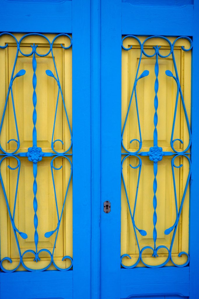 A blue front door with a decorated floral metal design