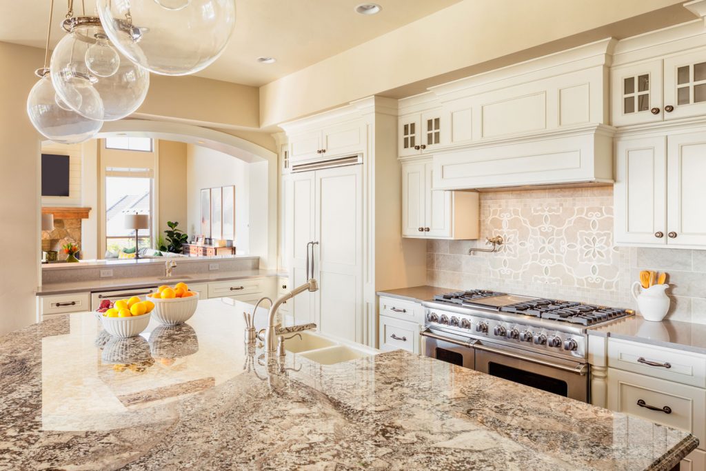 A classic inspired kitchen with brown countertop, beige painted cupboards and brown granite countertop