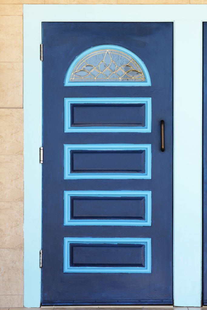 A huge front door panel with blue square designs and a light blue painted trim