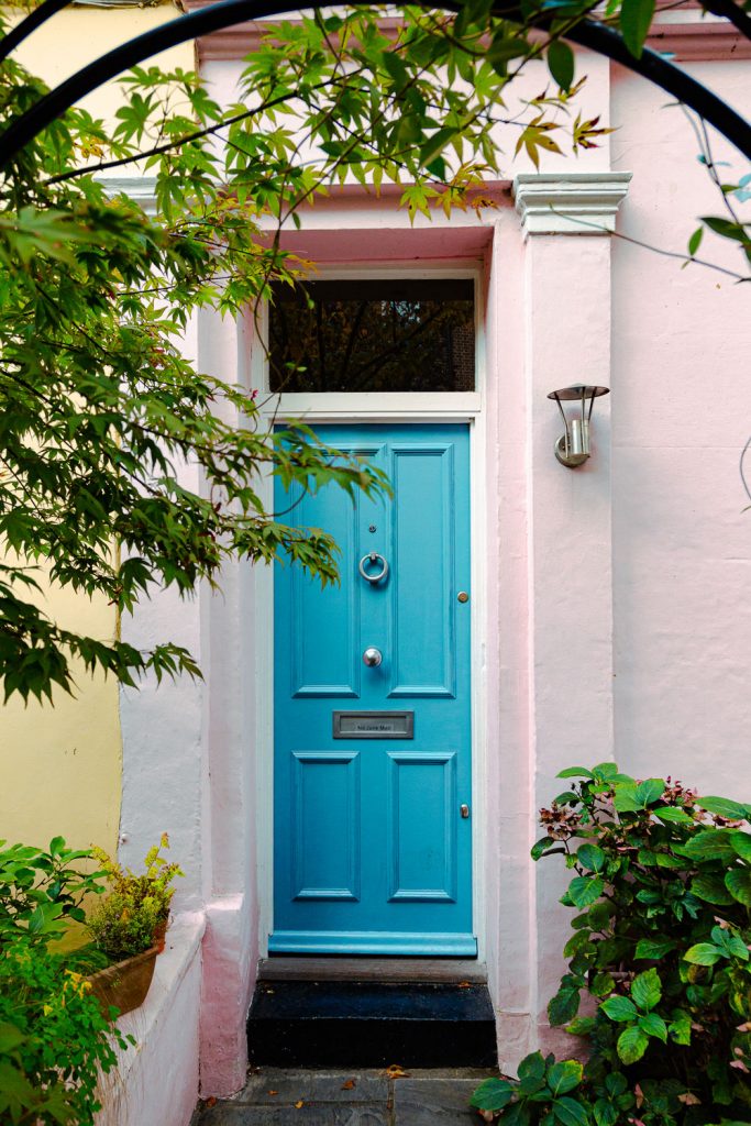 A narrow entryway to a blue front door of a small apartment building