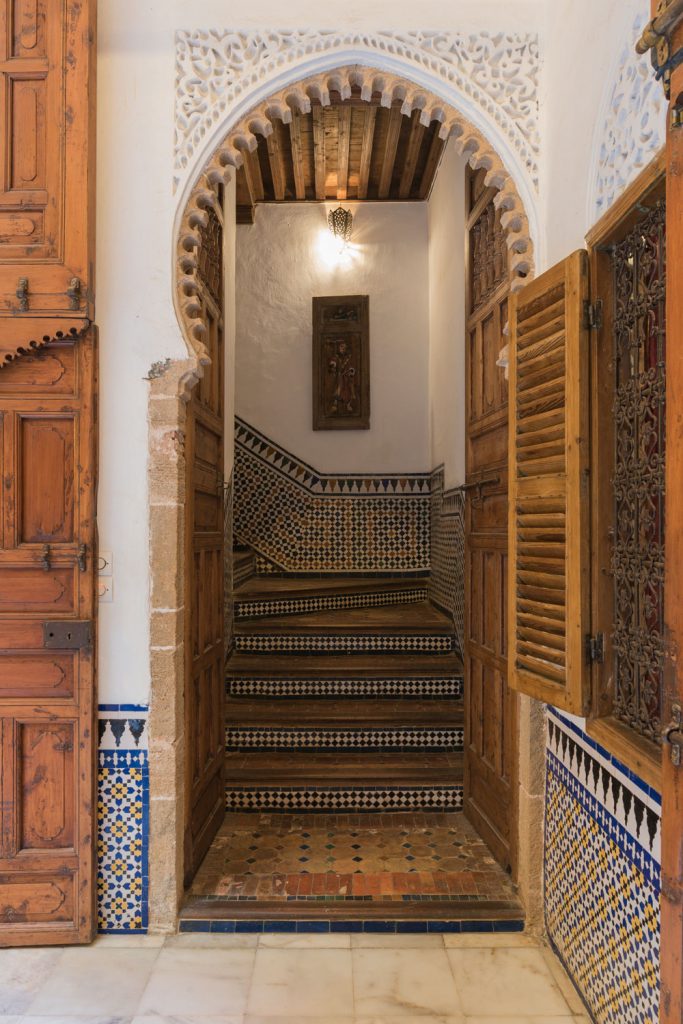 A stairway containing lots of Arabic patterned tiles and arched entryway