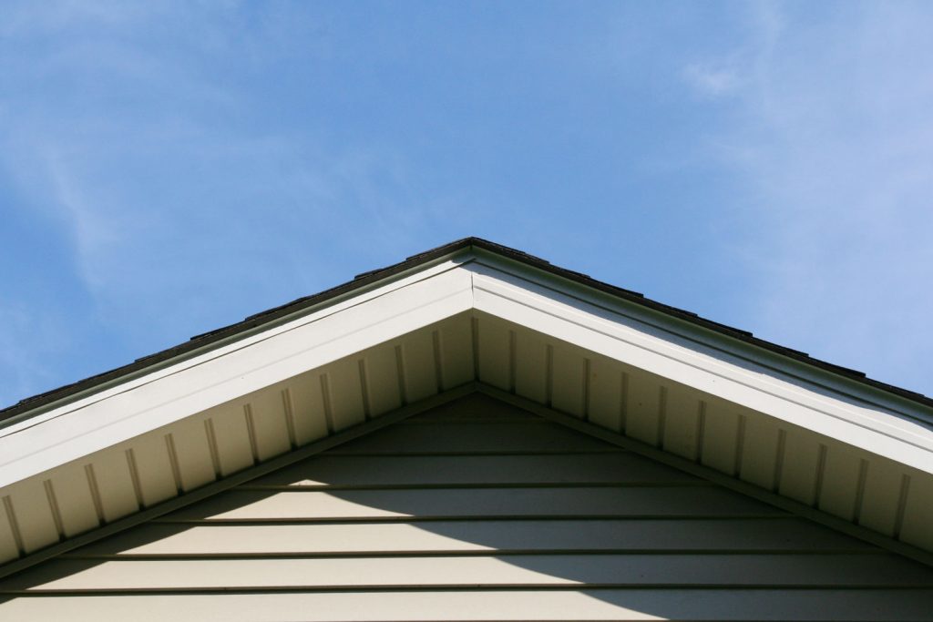Apex of a house showing the fascia board, soffit board and matching colored siding