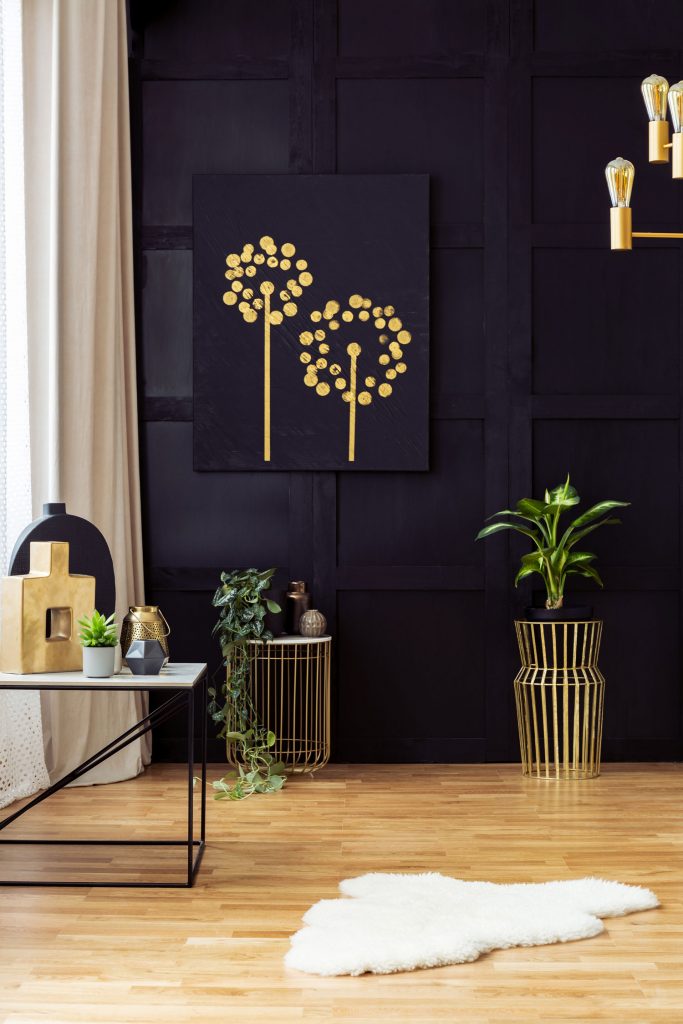 Elegant living room interior with golden accents, painting on a black wall, plants and fur rug.
