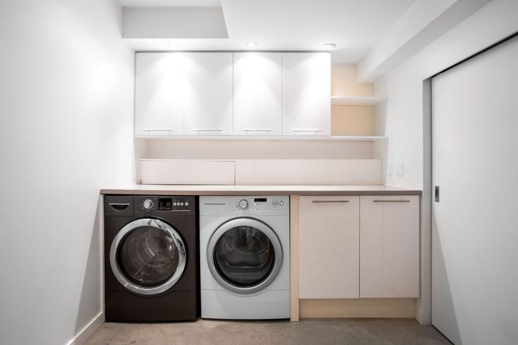 Interior of an empty laundry room with white painted walls and small cabinets