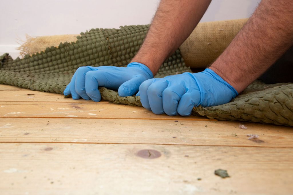 Man removing carpet underlay from a wooden floor.Home improvement project concept