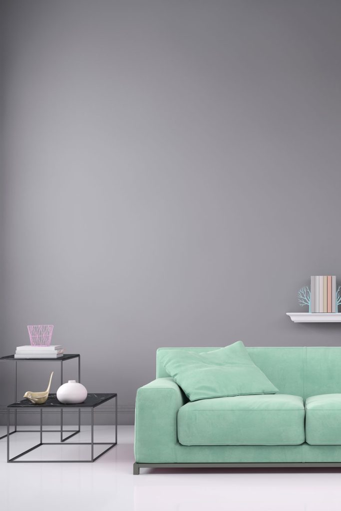 Minimalist inspired living room with teal sofas and a huge gray wall on the back