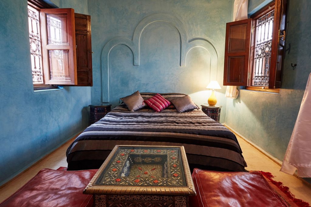 Narrow and cozy Moroccan bedroom with blue painted walls