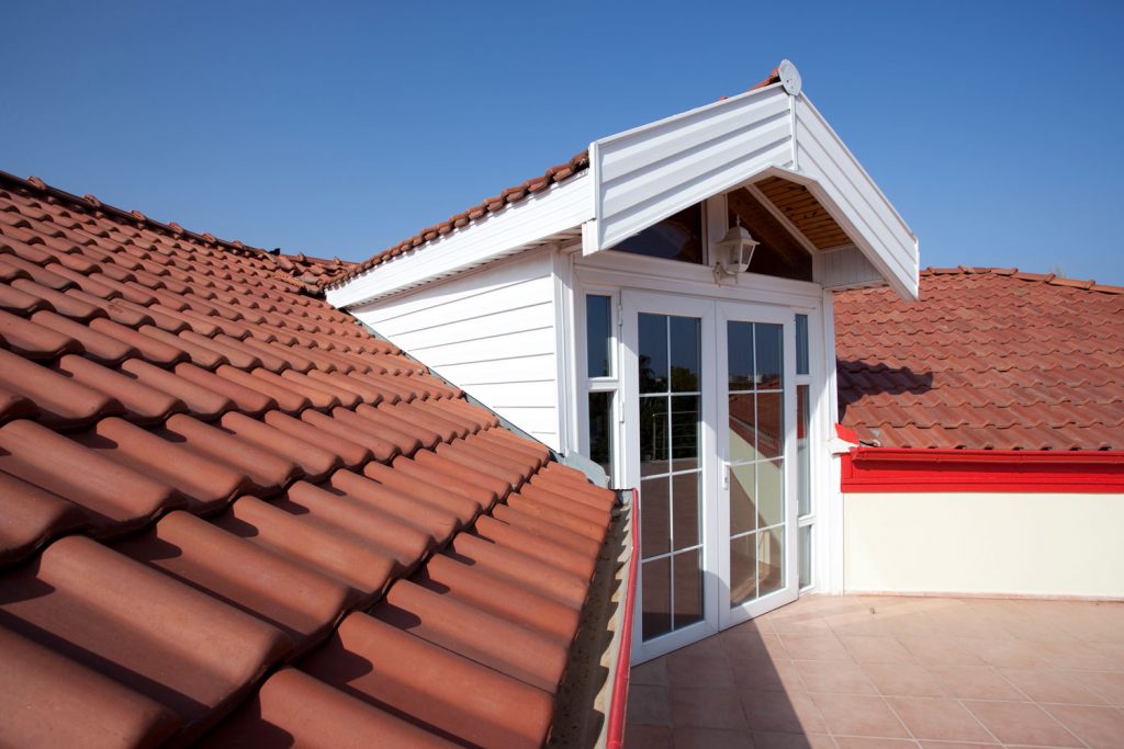 Red ceramic shingle tile roofing with a French door leading to the roof deck