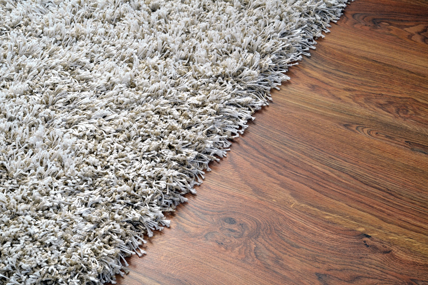 White shaggy carpet on brown wooden floor detail, Laminate Vs Carpet In The Living Room: Which To Choose