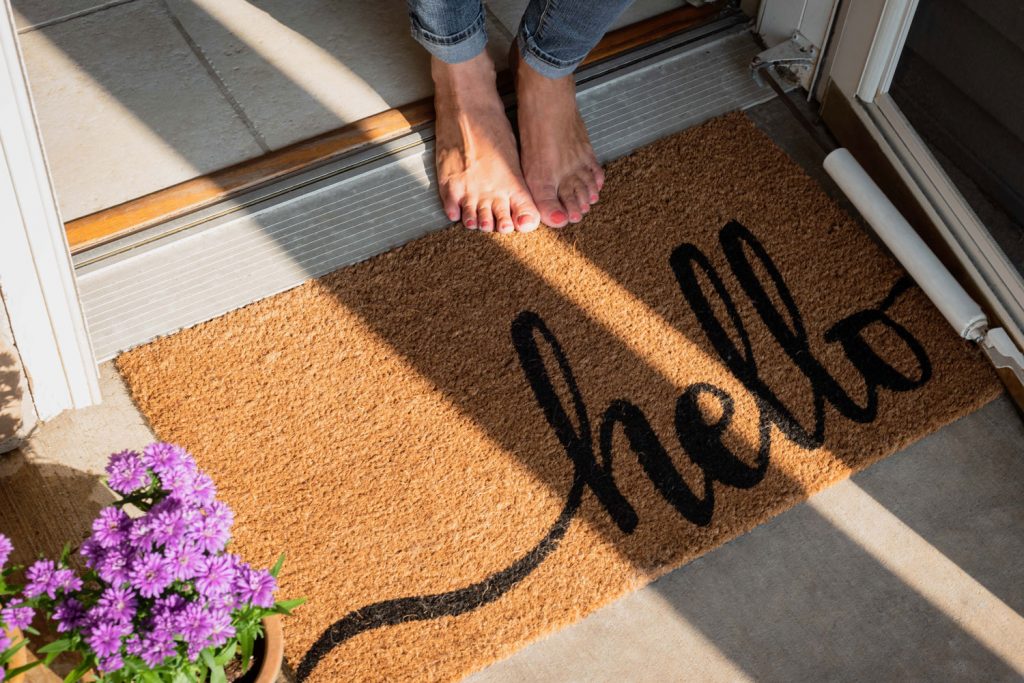 woman in bare feet standing at front door or new home with welcome mat
