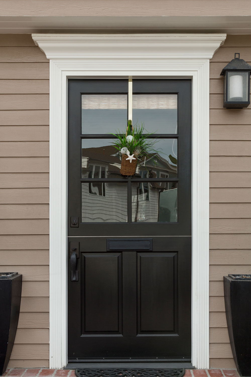 A black front door with a decorative plant and white door trims