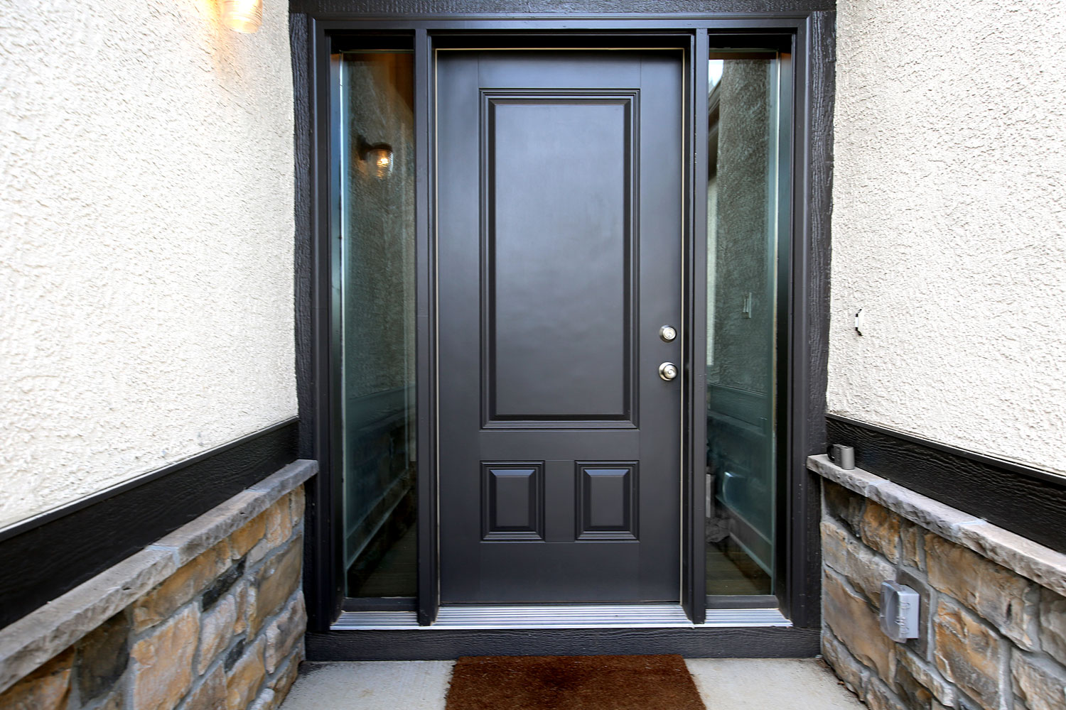 A black pivot door with glass panes on the sides