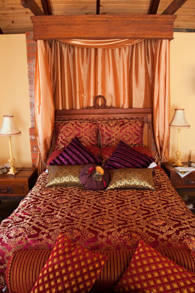 A cozy and luxurious two person bedroom with purple and red beddings
