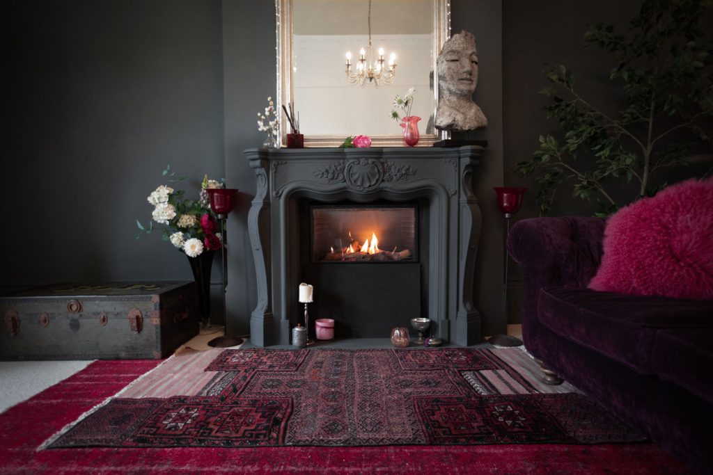 A gorgeous fireplace painted with gray and flowers on the side for decoration and burgundy carpet up front
