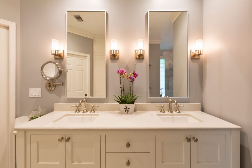 A gorgeous luxurious bathroom vanity area with wall mounted candles and gold planted fixtures