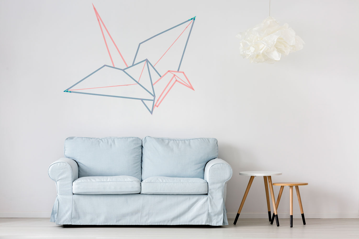 A two seater light blue colored sofa with an origami wall decor