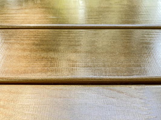 Empty wooden table in outdoor cafe with light reflectio