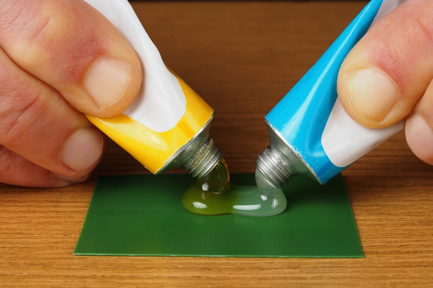 Hand holding two tubes with epoxy glue ingredients