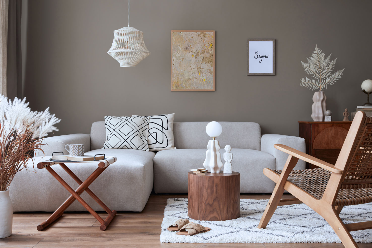 Interior of a stylish home decor with white modular sofas, rattan chairs and gray painted walls