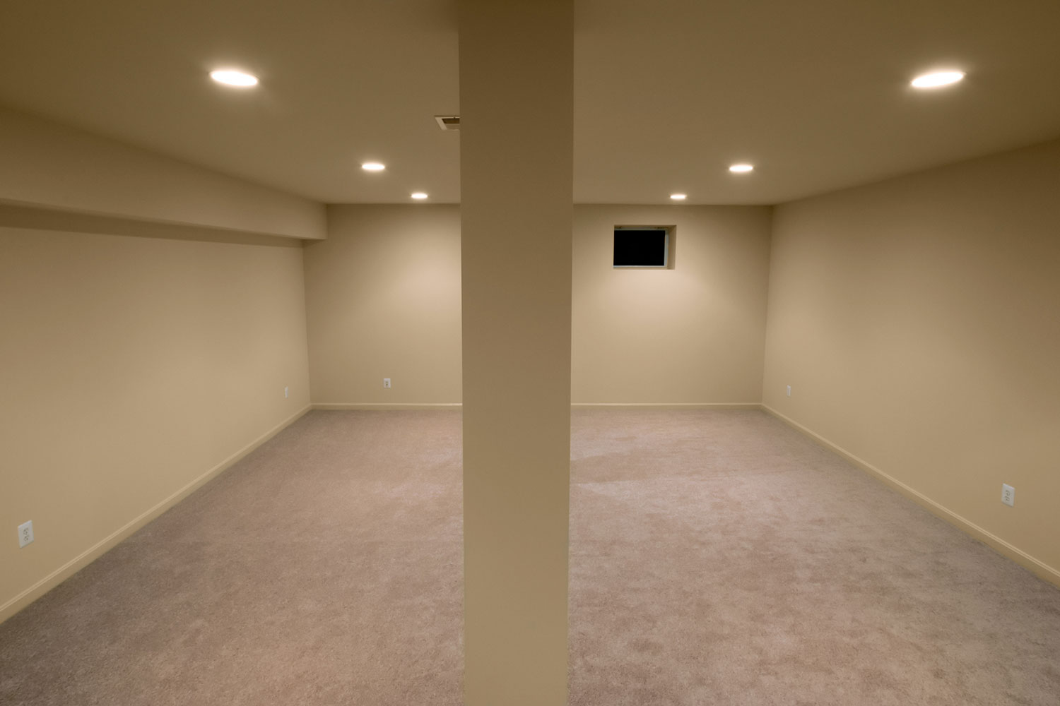 Interior of an empty basement with tan walls and recessed lighting