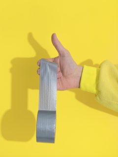 Male hand in yellow kugurumi holds Ultimate Gray tape sticks, Will Duct Tape Remove Paint From Walls?