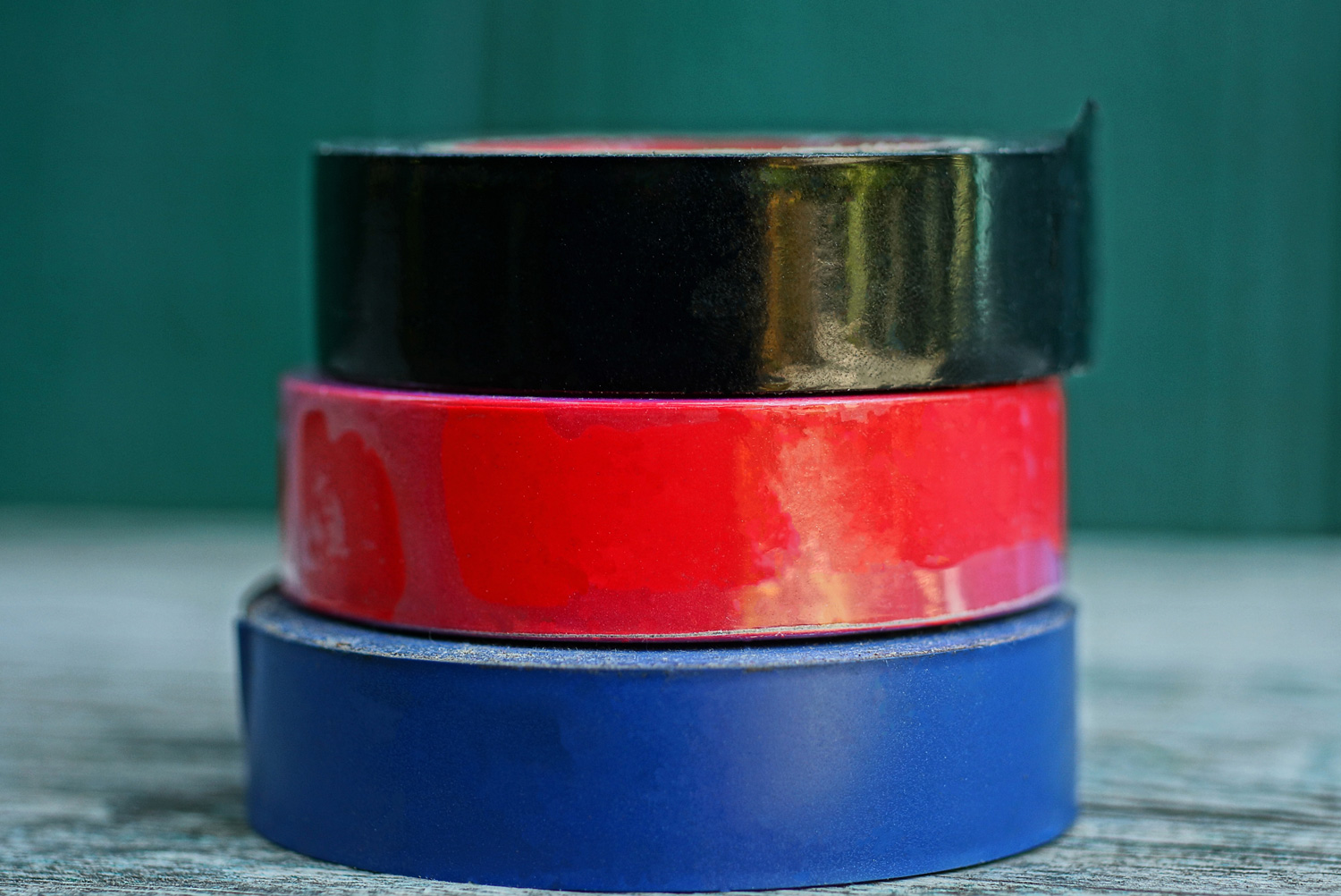 a set of colored rolls of electrical tape lies on a gray table