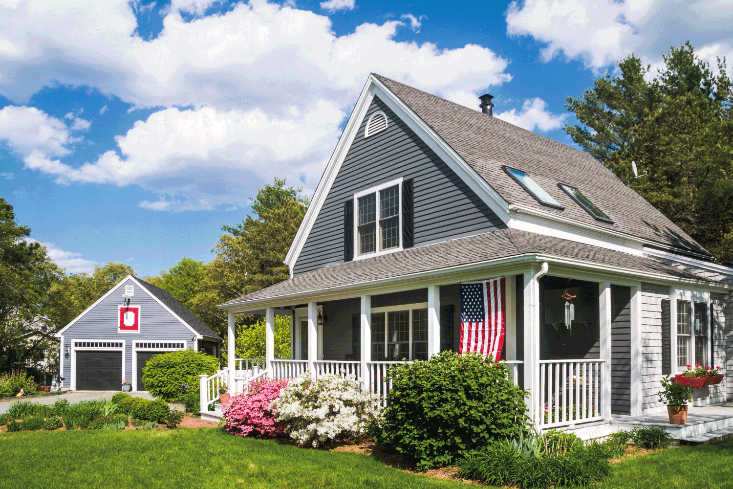 cape cod style house with American flag on the front porch